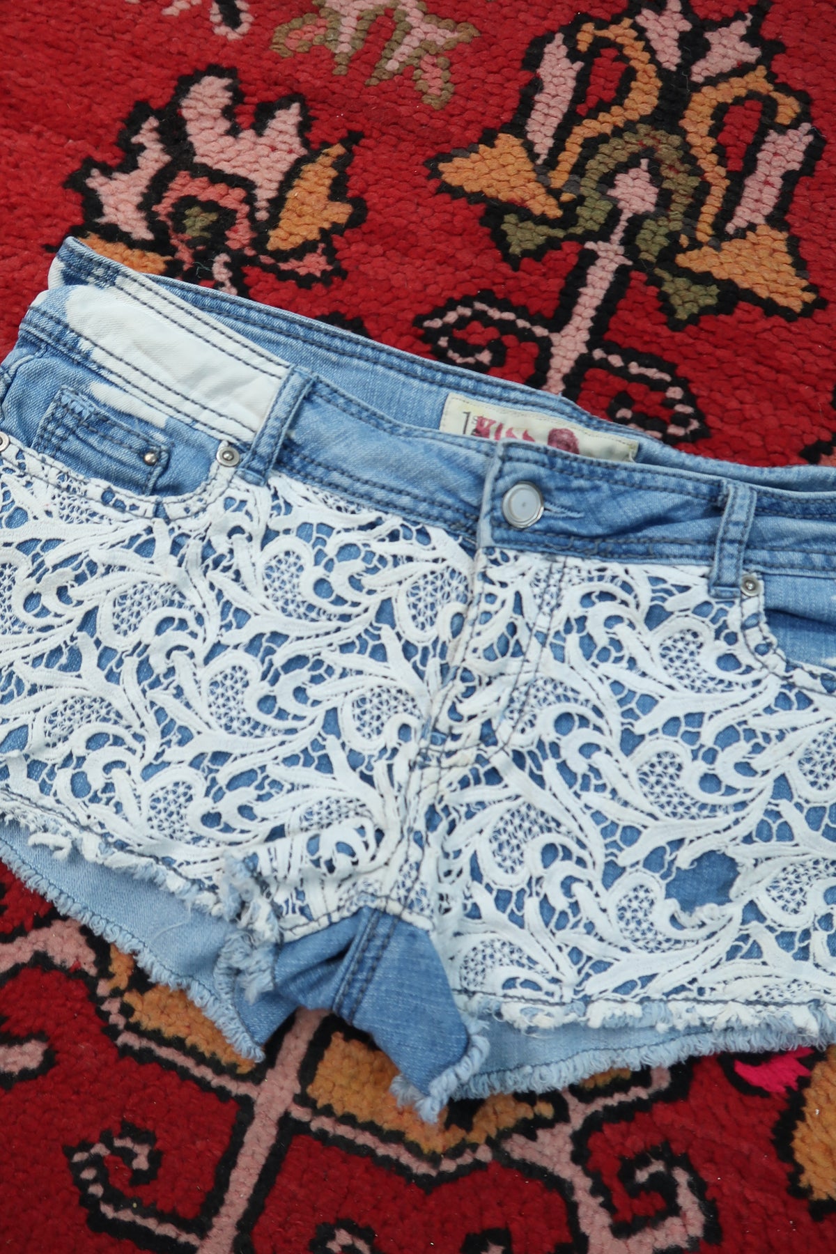 Women's vintage Y2K paisley lace denim shorts by Elektra Vintage, featuring distressed denim and intricate lace detailing.