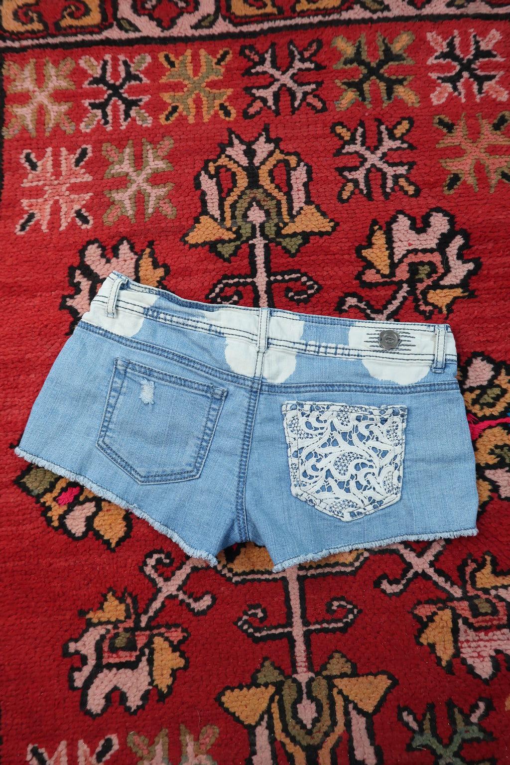 Women's vintage Y2K paisley lace denim shorts by Elektra Vintage, featuring distressed denim and intricate lace details.