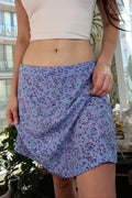 Person wearing a white sleeveless top and blue floral shorts indoors.