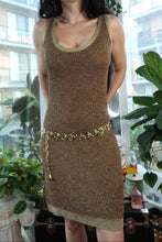 Load image into Gallery viewer, Woman wearing a gold dress with a chain detail in an indoor setting with plants.
