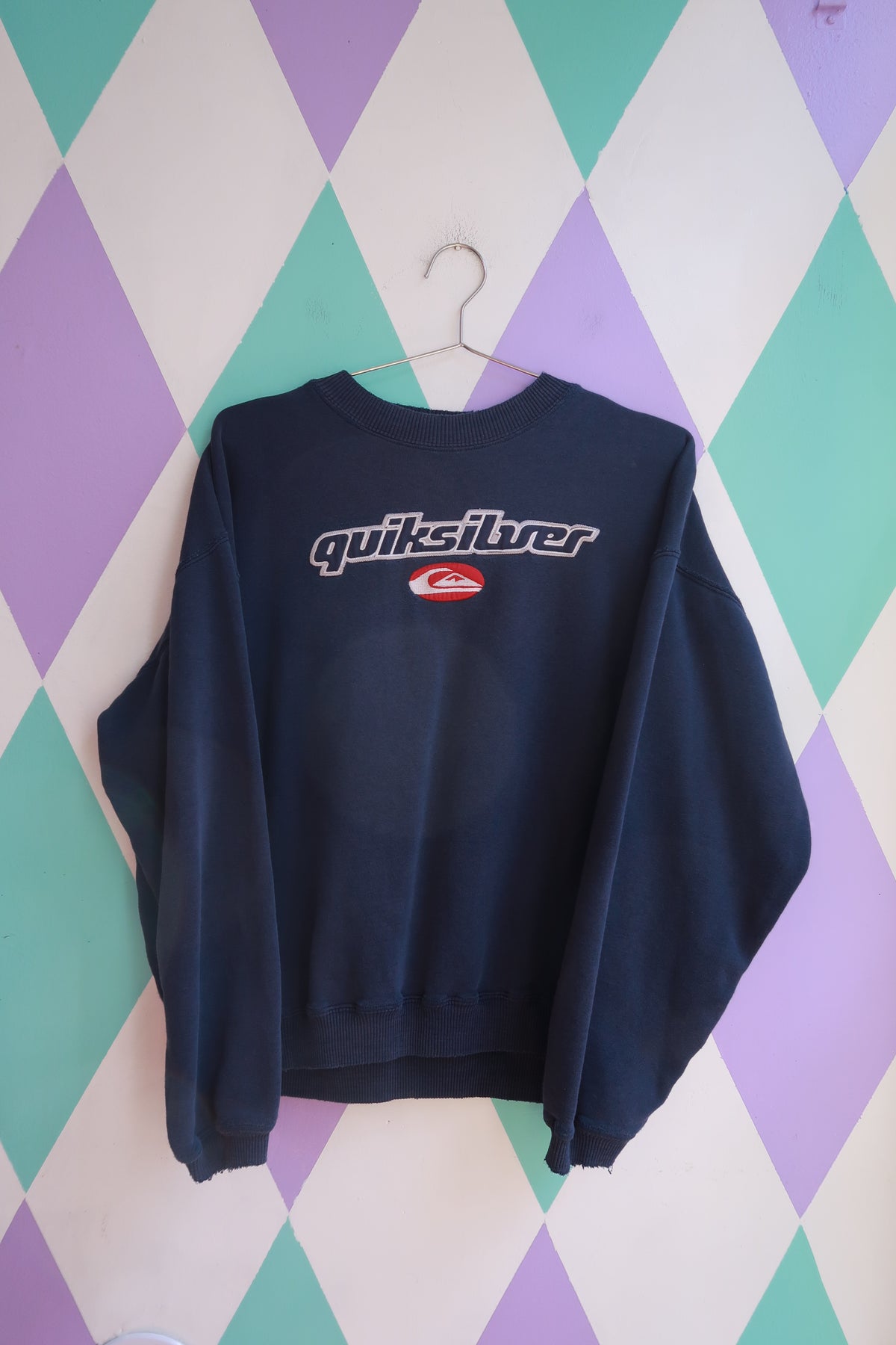 Vintage 2000s Quiksilver embroidered logo crewneck sweatshirt in navy, featuring classic branding and soft knit fabric.