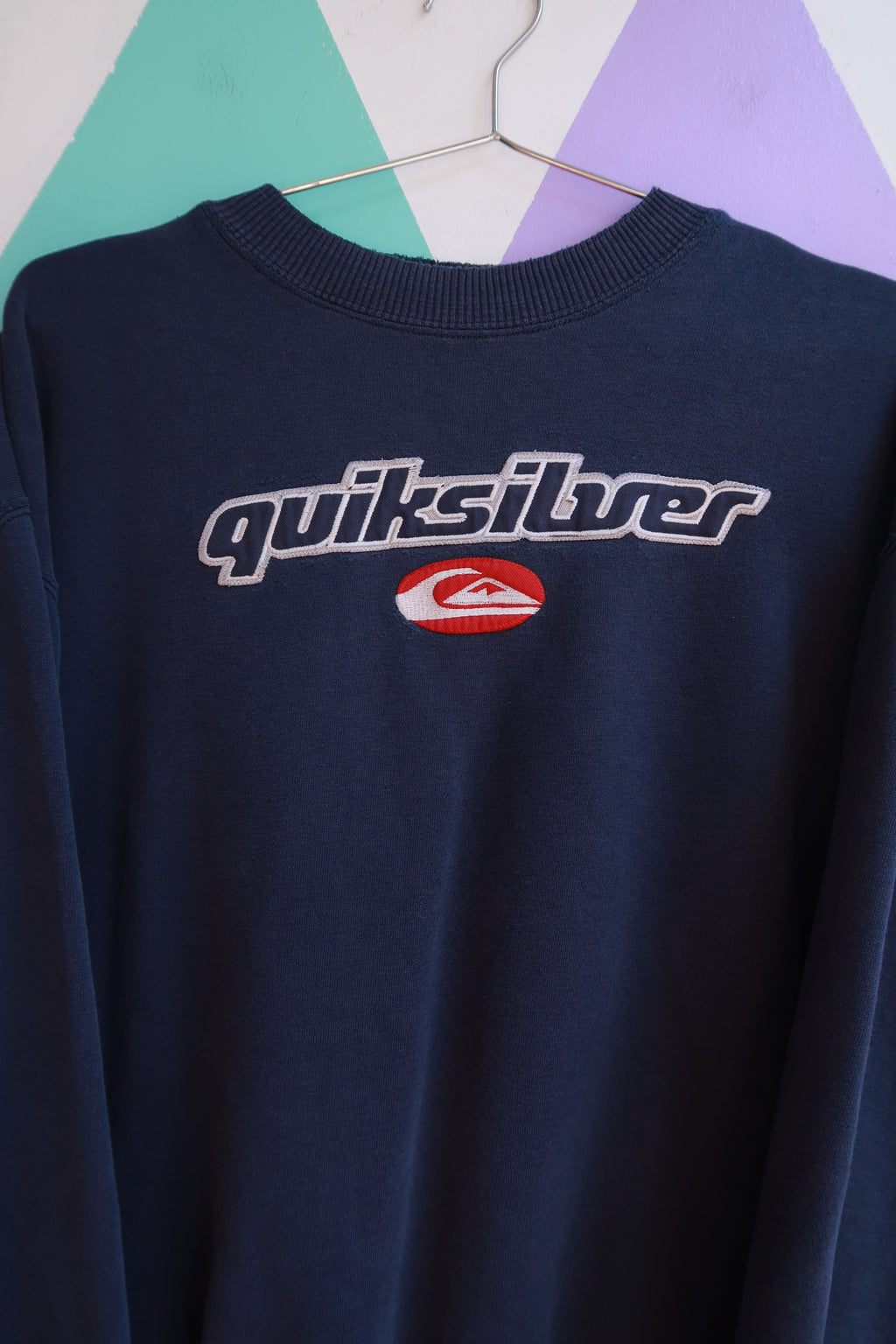 Vintage 2000s Quiksilver embroidered logo crewneck sweatshirt in charcoal gray, featuring classic surf brand branding and soft fabric.