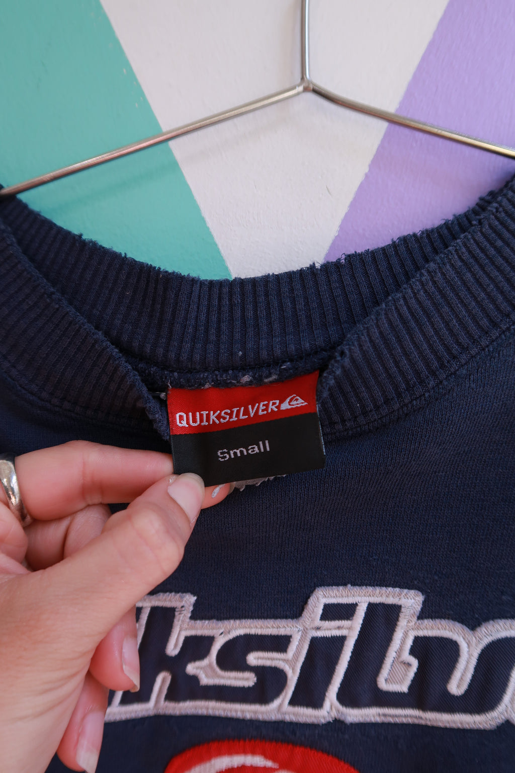 Vintage 2000s Quiksilver embroidered logo crewneck sweatshirt with classic design and soft fabric, displayed on a hanger.