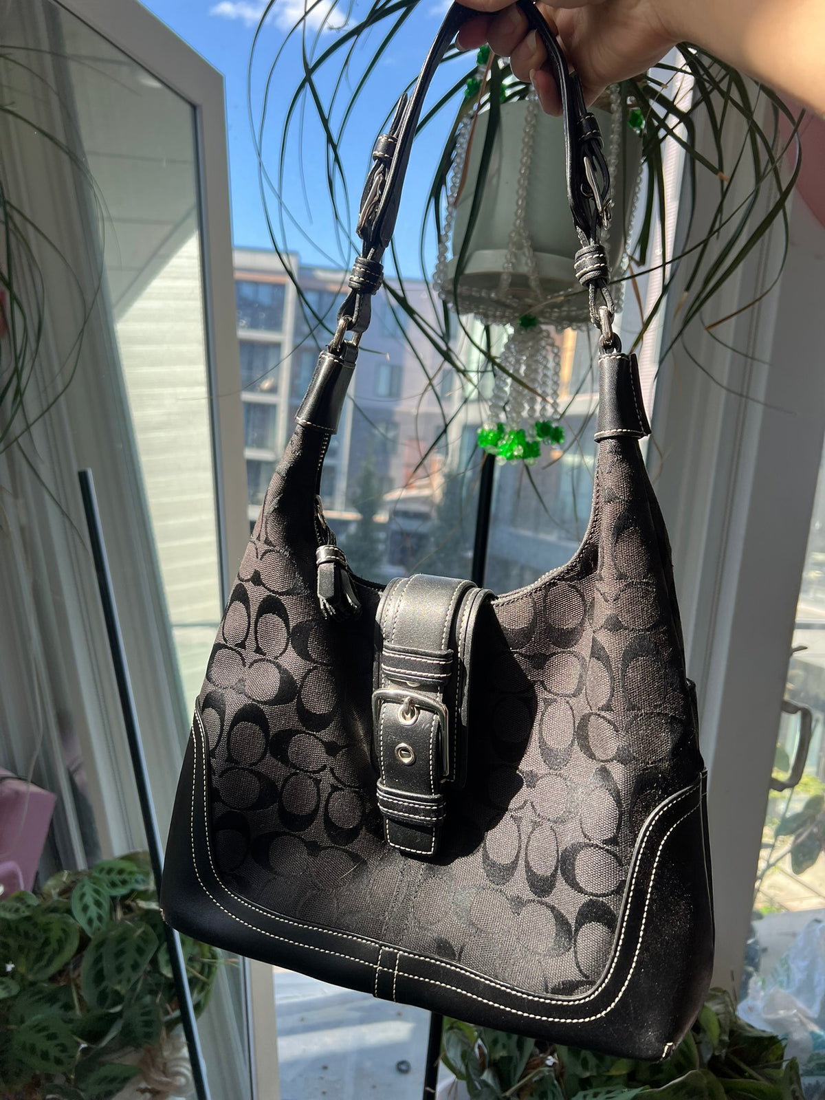 Black leather Hamilton Hobo shoulder bag by Coach, showcasing its sleek design and spacious interior.