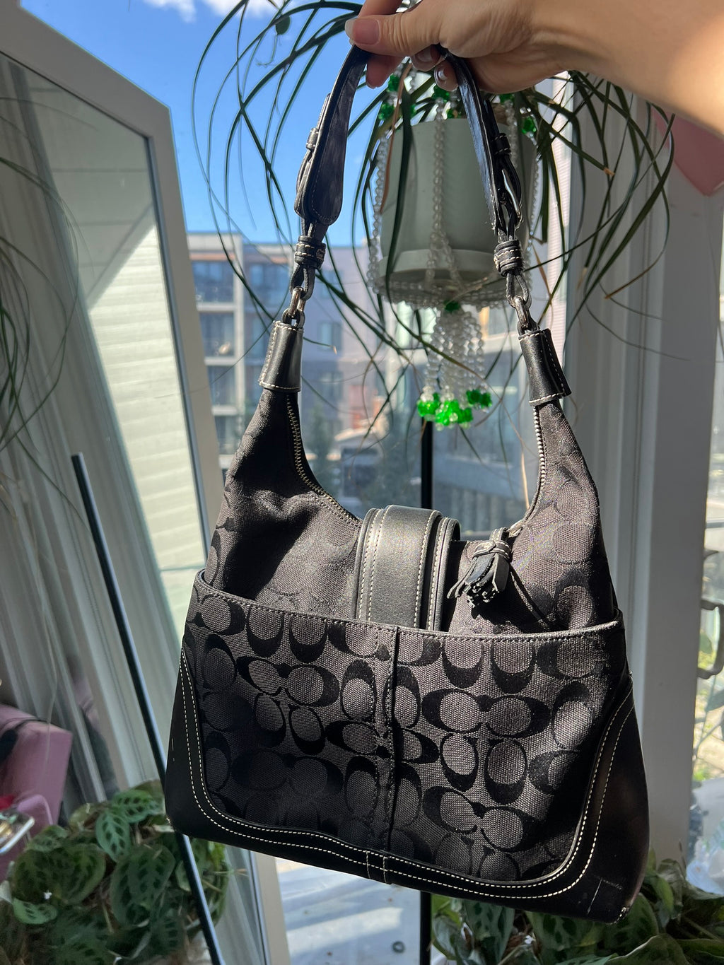 Black leather Hamilton Hobo shoulder bag by Coach, featuring a sleek design and spacious interior, displayed on a neutral background.
