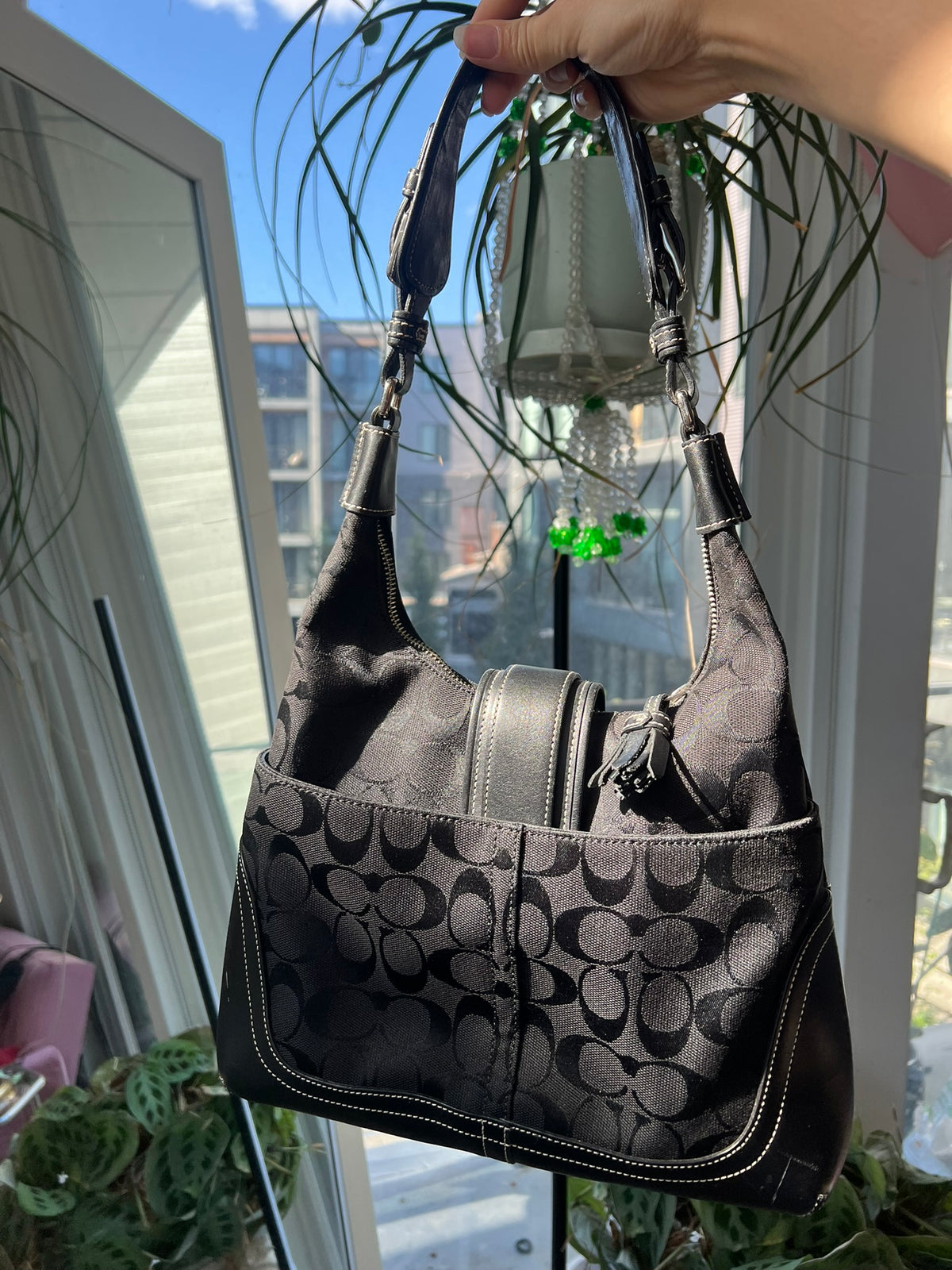 Black leather Hamilton Hobo shoulder bag by Coach, featuring a sleek design and spacious interior, displayed on a neutral background.