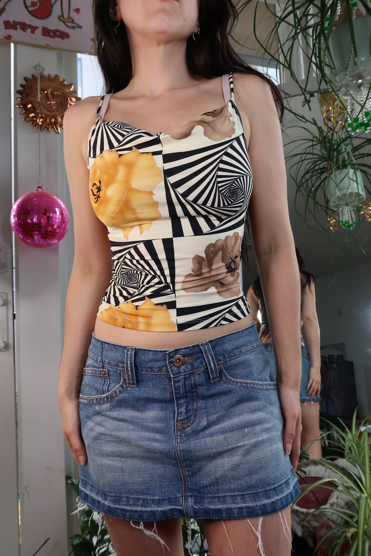Woman wearing a patterned top and denim skirt with a blurred background